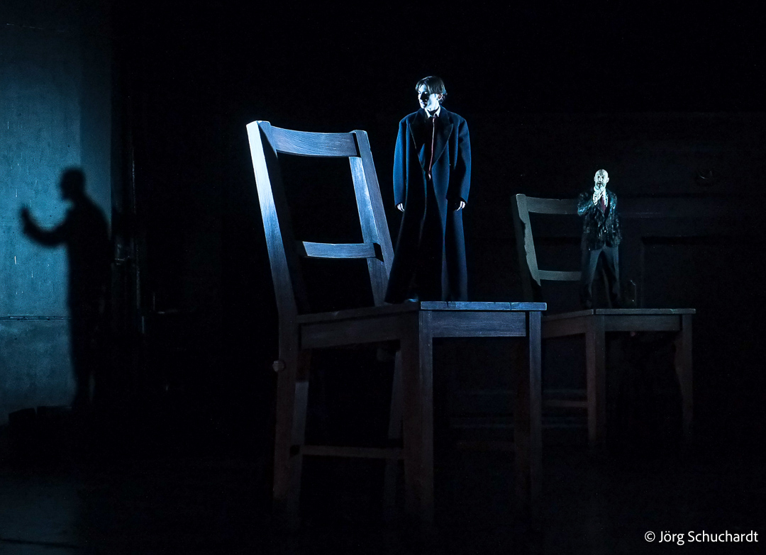 In shadowy brilliance, Andreas Greoetzinger embodies Porfiry interrogating Gustav Lindh's Raskolikov on giant moving chairs at Dramaten